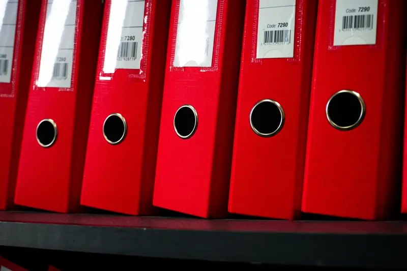 A row of red document folders on a shelf