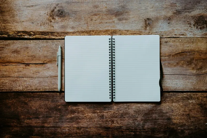 An open notebook and a pen on a wooden table